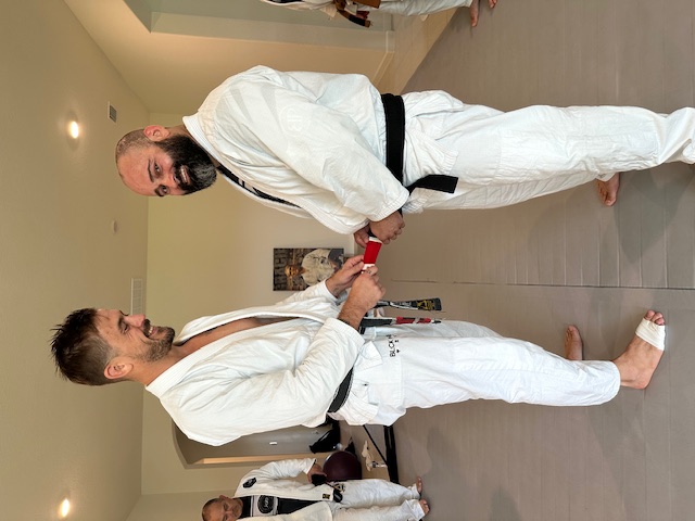 1st Degree from Chris Burns. I owe a lot ot Chris. He helped me refine all of my technique, and showed me details I was missing.  He helped me understand the concepts and principles behind Rickson's Jiu Jitsu, and also how Rickson's Jiu Jitsu has evolved from when he ran an academy with Henry Akins to now. Chris gave me hours upon hours of instruction and fine tuning.  He tested me for my 1st degree over the course of 3 years, and for the final stage of the test, I went with him on tour and was tested for 2.5 weeks straight, including being tested at Rickson's house.  I am honored and humbled to be ranked under Chris, and am forever grateful.  I look forward to continuing to learn from Chris and respresent him. It is an honor to be part of this journey. - Photo 1